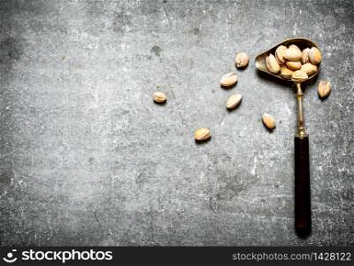 Pistachios in an old spoon. On the stone table. Pistachios in an old spoon.