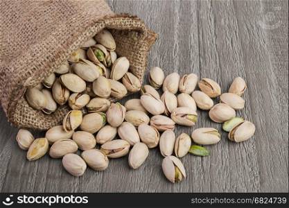 Pistachios nuts in burlap sack on vintage wooden table