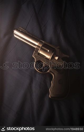 Pistol gun on bed sheet still life crime thriller book cover design.