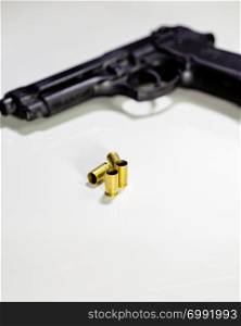 Pistol with 9mm shell casings on white table