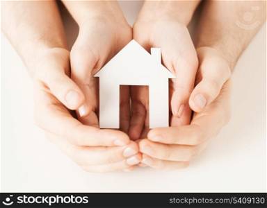 pisture of man and woman hands holding paper house