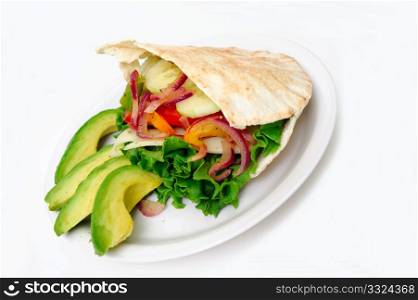 Pita bread sandwich with lettuce, swiss cheese, grilled onions and bell pepper, tomatoes, cucumber abd Avacado on a white plate. Flat Bread Sandwich