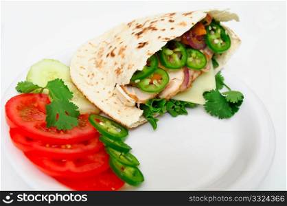 Pita bread sandwich with lettuce, swiss cheese, grilled onions and jalapeno pepper, tomatoes, cucumber on a white plate. Pita Sandwich