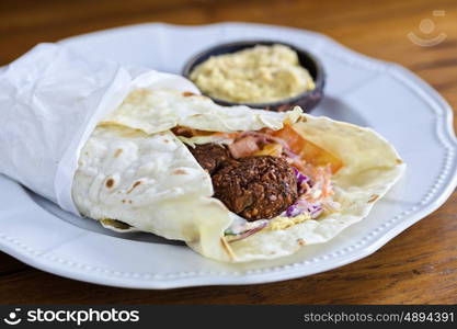 Pita bread with falafel and fresh vegetables on wooden table&#xA; &#xA;&#xA;