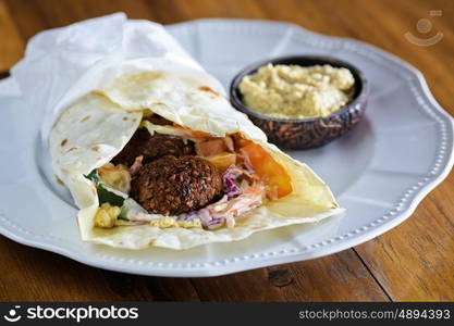 Pita bread with falafel and fresh vegetables on wooden table&#xA; &#xA;&#xA;