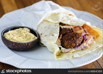 Pita bread with falafel and fresh vegetables on wooden table&#xA; &#xA;&#xA;