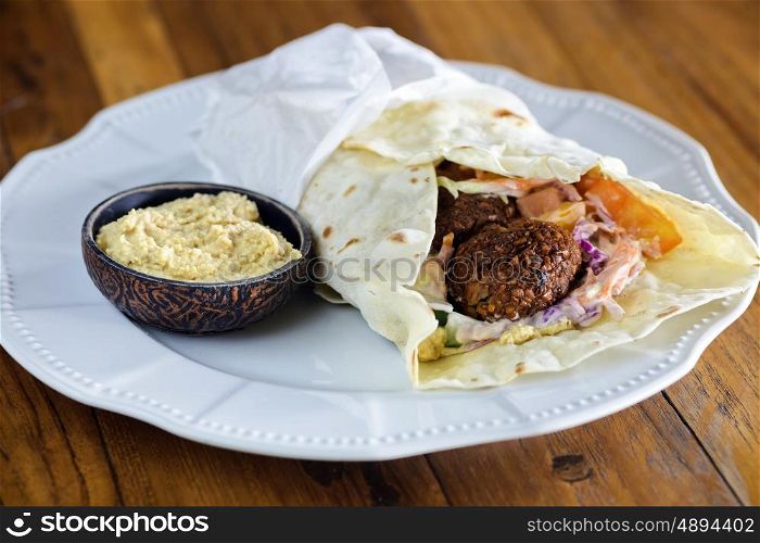 Pita bread with falafel and fresh vegetables on wooden table&#xA; &#xA;&#xA;