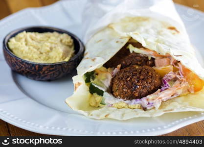 Pita bread with falafel and fresh vegetables on wooden table&#xA; &#xA;&#xA;