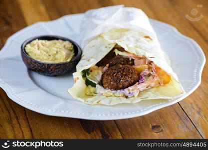 Pita bread with falafel and fresh vegetables on wooden table&#xA; &#xA;&#xA;