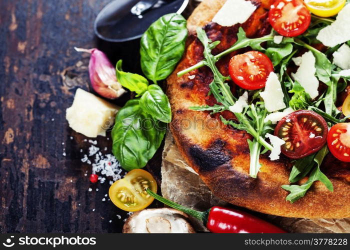 pizza and fresh italian ingredients on a dark background