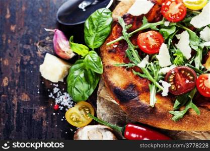 pizza and fresh italian ingredients on a dark background