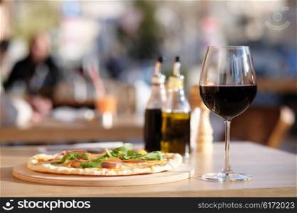 Pizza and glass of red wine in outdoor restaurant