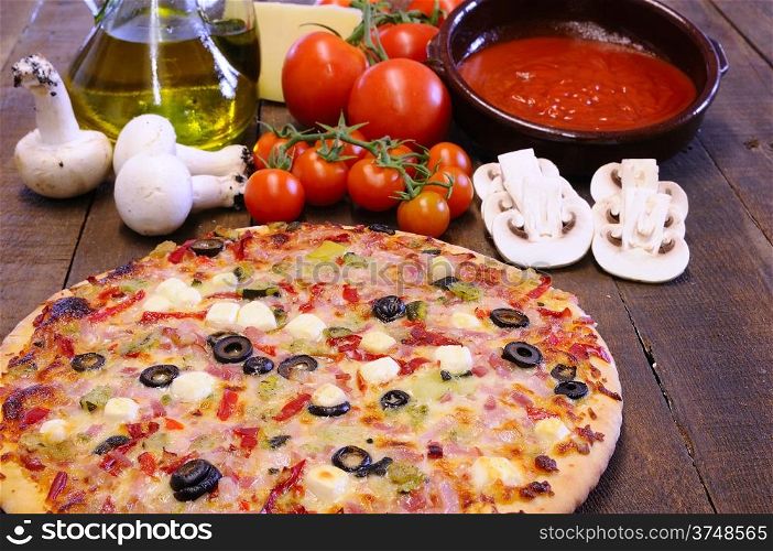 Pizza and ingredients on the kitchen table.