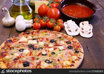 Pizza and ingredients on the kitchen table.