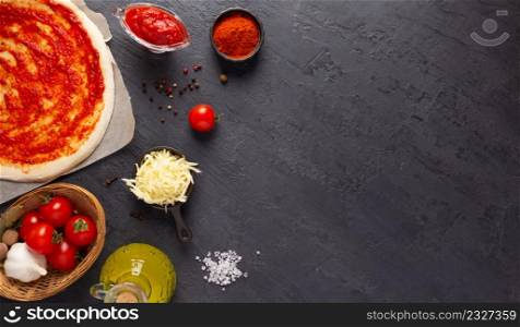 Pizza and sauce homemade cooking or baking on table. Dough pizza at slate tabletop background. Recipe concept in kitchen