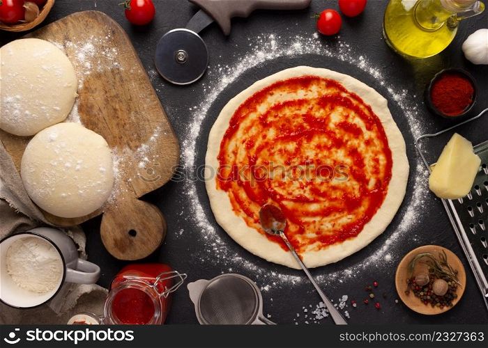 Pizza and sauce homemade cooking or baking on table. Dough pizza at slate tabletop background. Recipe concept in kitchen