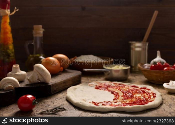 Pizza and sauce homemade cooking or baking on table. Dough pizza at wooden tabletop background. Recipe concept in kitchen