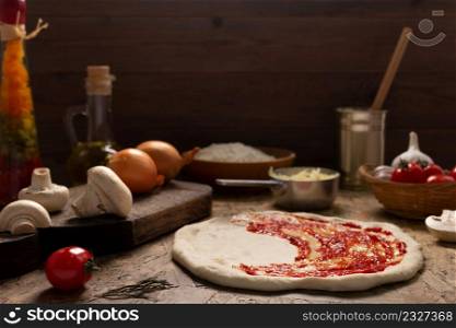 Pizza and sauce homemade cooking or baking on table. Dough pizza at wooden tabletop background. Recipe concept in kitchen