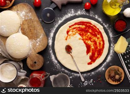 Pizza and sauce homemade cooking with ingredients at table. Dough pizza on tabletop background. Recipe concept in kitchen