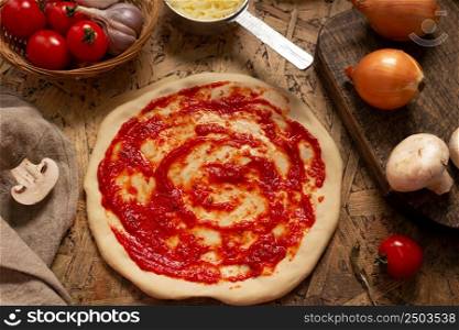 Pizza and sauce homemade cooking with ingredients at table. Dough pizza on tabletop background. Recipe concept in kitchen