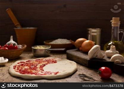 Pizza and tomato sauce or ketchup with ingredients at table. Pizza cooking on tabletop background. Recipe concept in kitchen