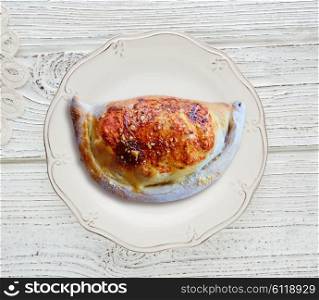 Pizza Calzone folded as a patty on a wooden board table