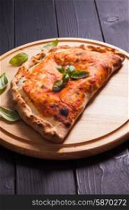 Pizza calzone with basil leaves close up