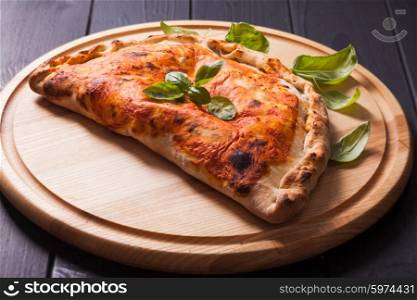 Pizza calzone with basil leaves close up. The Pizza calzone