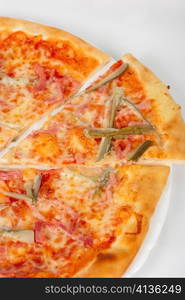 pizza closeup with boiled sausage, ham, marinated gherkin and mozzarella cheese