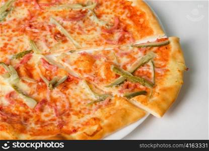 pizza closeup with boiled sausage, ham, marinated gherkin and mozzarella cheese