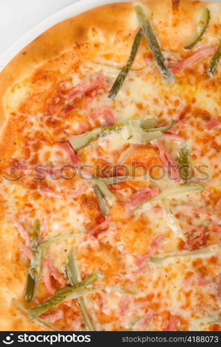 pizza closeup with boiled sausage, ham, marinated gherkin and mozzarella cheese