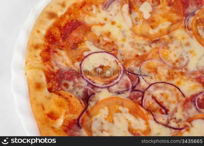 pizza closeup with salami, tomato, onion and mozzarella cheese