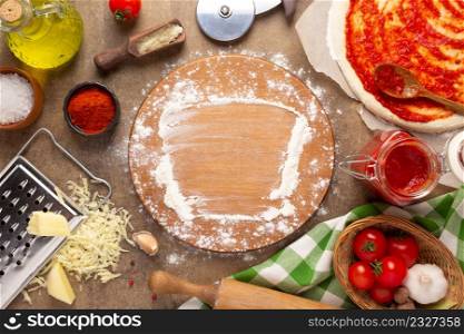 Pizza cutting board and flour homemade cooking or baking on table. Pizza ingredient at tabletop background top view. Recipe concept in kitchen