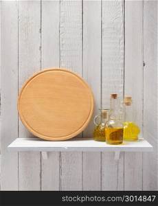 pizza cutting board and oil at shelf on wooden background
