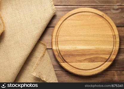 pizza cutting board and sack hessian cloth at rustic wooden plank board background, top view