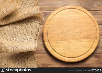 pizza cutting board and sack hessian cloth at rustic wooden plank board background, top view