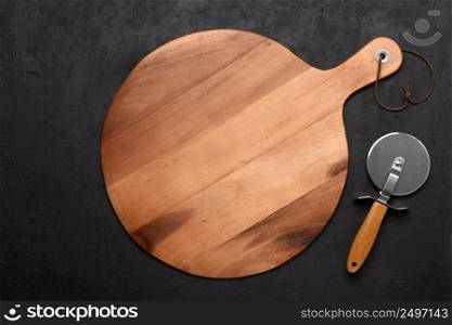 Pizza cutting board with pizza knife on dark rustic background