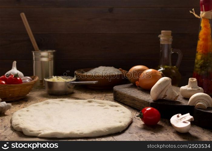 Pizza homemade cooking with ingredients on table. Dough pizza at tabletop background. Recipe concept in kitchen