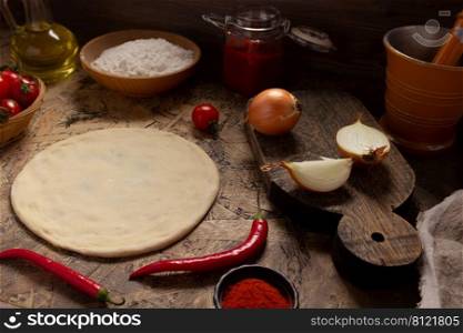 Pizza homemade cooking with ingredients on table. Dough pizza at tabletop background. Recipe concept in kitchen