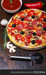 Pizza on wooden table with ingredients and cutter