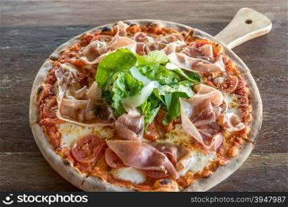 pizza parma ham and rocket salad on wooden table