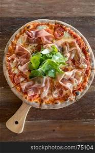 pizza parma ham and rocket salad on wooden table