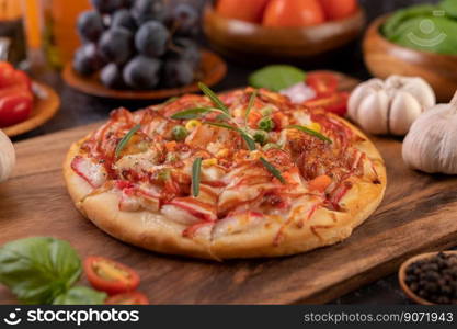 Pizza placed on a wooden plate complete with pepper seeds. Tomatoes and garlic. Selective focus.