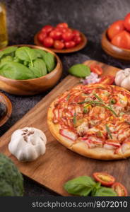 Pizza placed on a wooden plate complete with pepper seeds. Tomatoes and garlic. Selective focus.