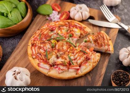 Pizza placed on a wooden plate complete with pepper seeds. Tomatoes and garlic. Selective focus.