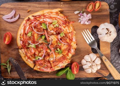 Pizza placed on a wooden plate complete with pepper seeds. Tomatoes and garlic.  Top view.