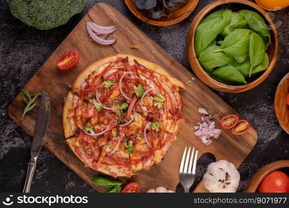 Pizza placed on a wooden plate complete with pepper seeds. Tomatoes and garlic.  Top view.