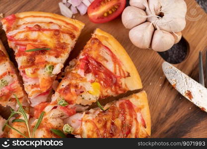 Pizza placed on a wooden plate complete with pepper seeds. Tomatoes and garlic. Top view.