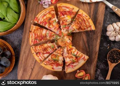 Pizza placed on a wooden plate complete with pepper seeds. Tomatoes and garlic. Top view.