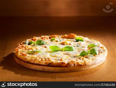 Pizza quattro fromaggi with basil on wooden background